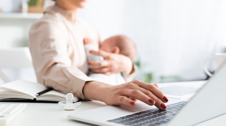 new mother breastfeeding while working on a laptop